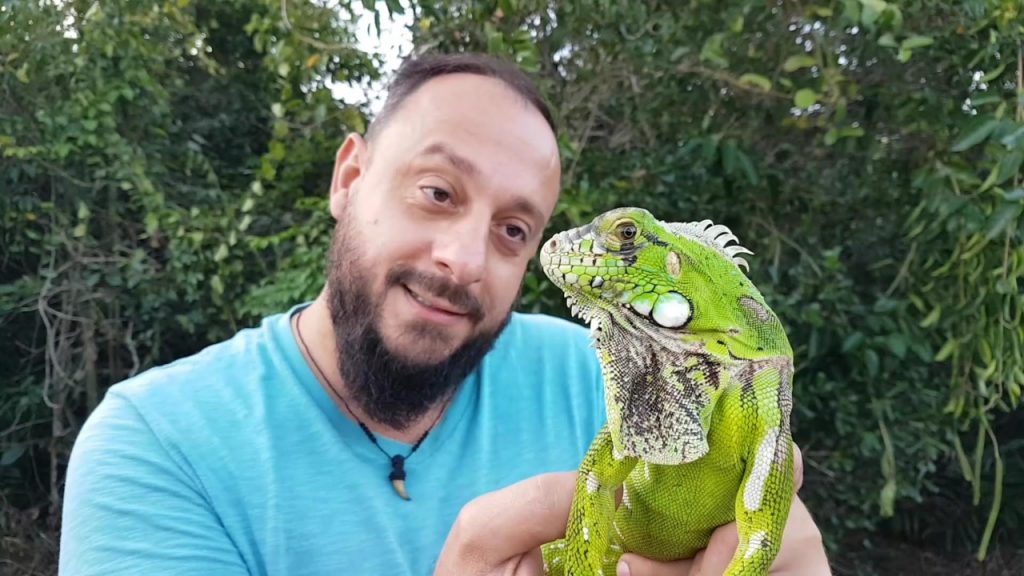 Biólogo Henrique segura uma iguana